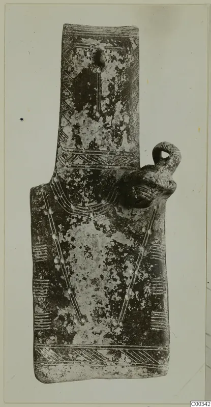 Flat idol-shaped object with incised chevron and band patterns and a loop on its right edge