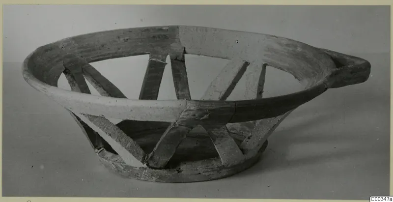 Shallow pottery bowl with a wide flaring rim and a handle, photographed from the side.