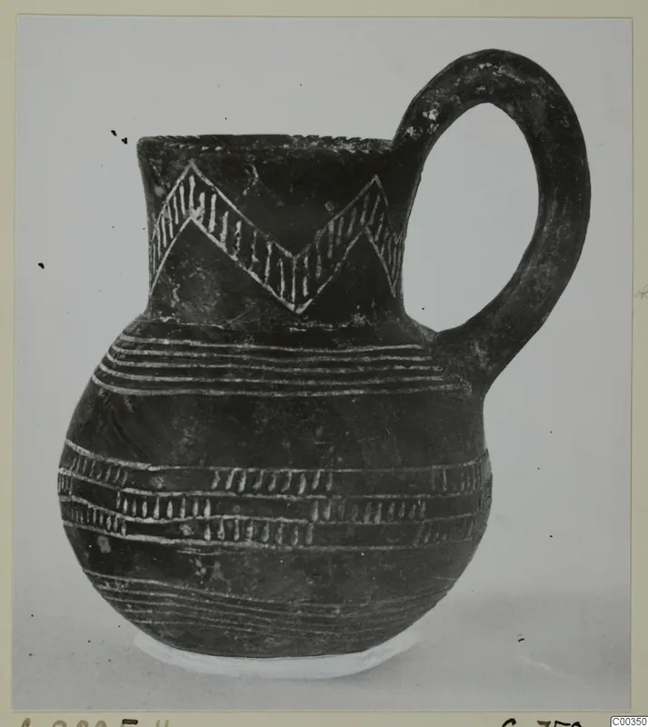 Black polished jug with a loop handle and white-incised zigzag and horizontal band decoration