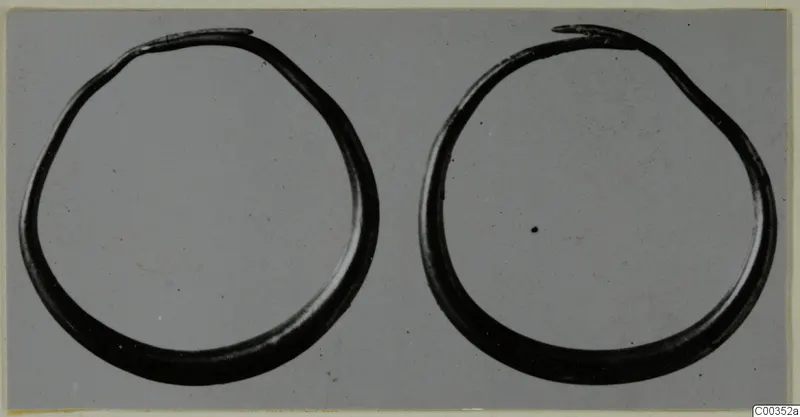 Two open gold rings from the Kastros tombs at Lapithos, photographed side by side on a grey background.