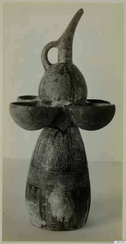 Pottery vessel with a tall curved spout, loop handle and two side cups, decorated with incised patterns