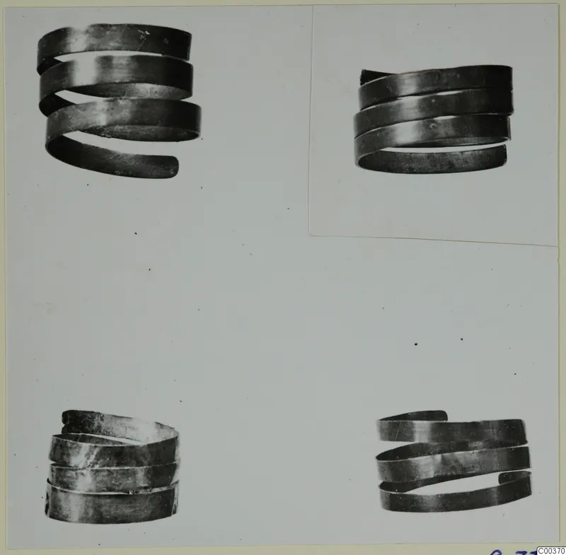 Four spiral metal rings from the Vrysi tou Barba tombs at Lapithos, shown on a photo mount