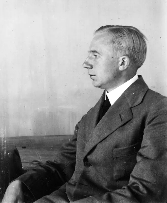 Portrait of a man seated in profile facing left, wearing a suit and collared shirt, in Nicosia.