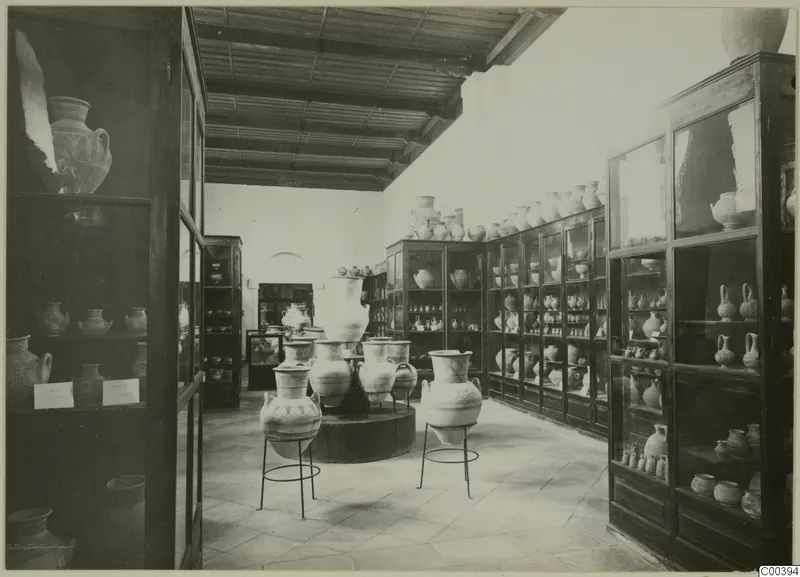 Interior of the Cyprus Museum with glass cabinets of pottery and large decorated jars on metal stands