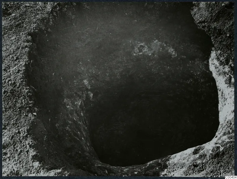 Tomb at Milia: looking down into a tomb chamber during excavation, with pale stones visible near the top