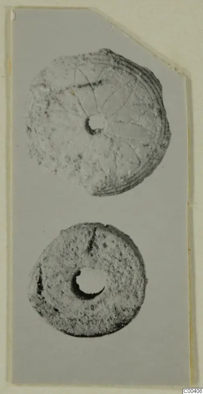 Two disc-shaped objects with central holes from Lapithos; the upper one has incised radiating lines and concentric grooves on its rim.