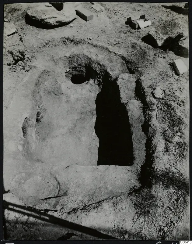 Tomb 307 at Lapithos, Vrysi tou Barba, during excavation, showing a dark rectangular tomb opening cut into the soil