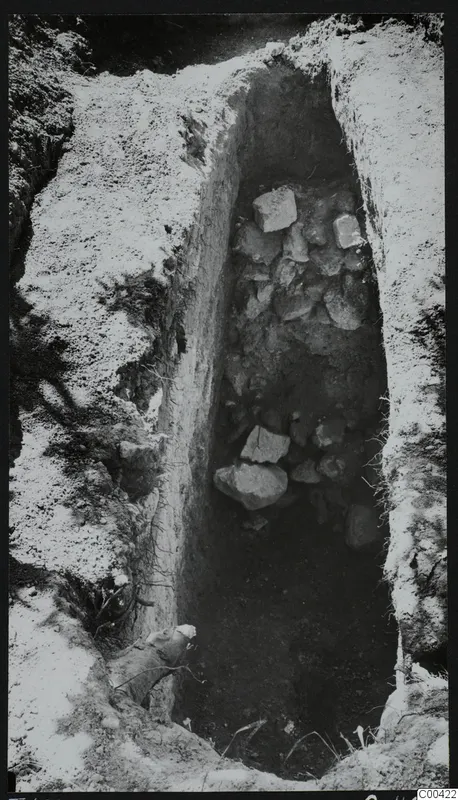 Excavation of Tomb 428 at Lapithos, showing a narrow cut in the earth filled with stones.