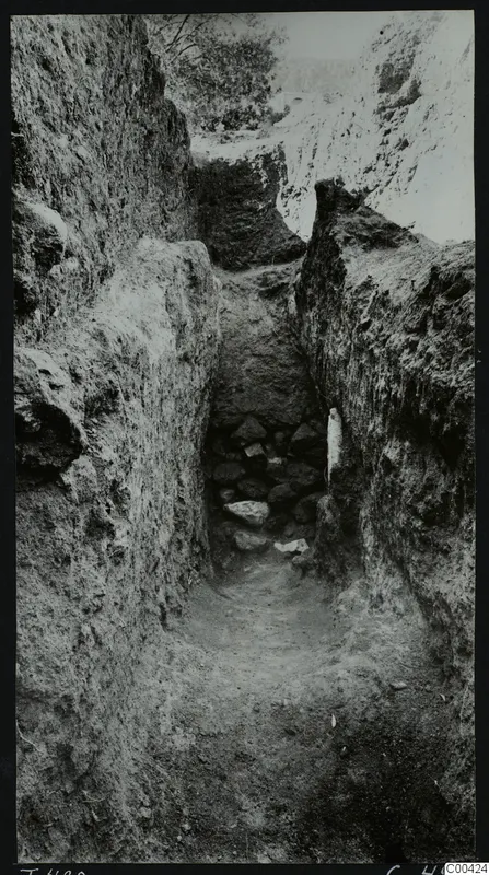 Dromos of Tomb 420 at Lapithos Kastros, a narrow cut passage with stones at its far end