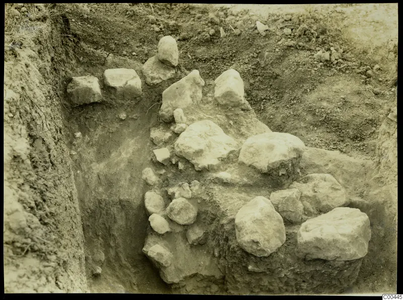 Excavation trench at Plakes, Lapithos, with large limestone blocks and stones exposed in the soil