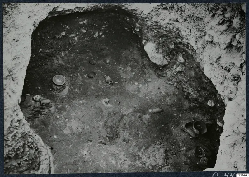Tomb 66 at Marion during excavation, with small vessels and stones lying on the chamber floor