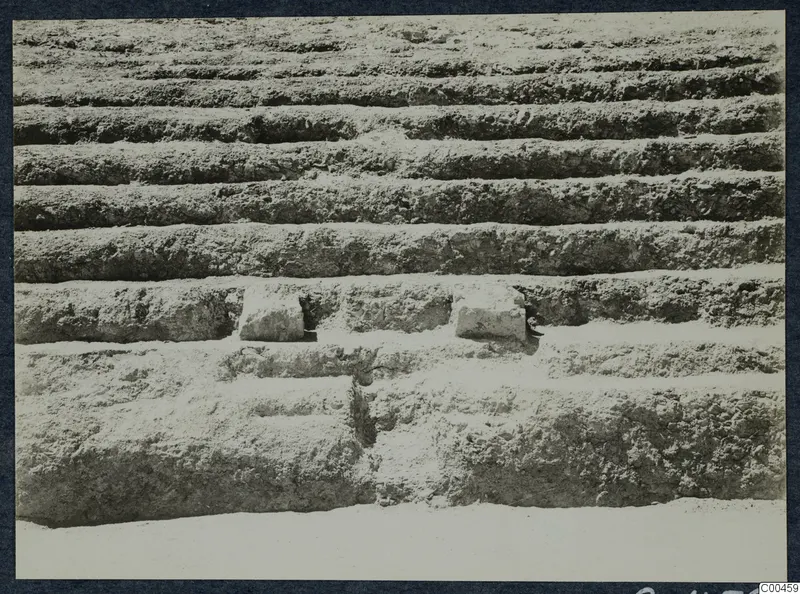 Stepped horizontal tiers of excavated earth at the theatre at Soli, with two stone blocks set into one step.