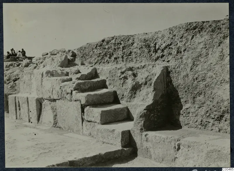 Stone steps of cut blocks rising against an excavated earth bank at the theatre at Soli, with people at top left.