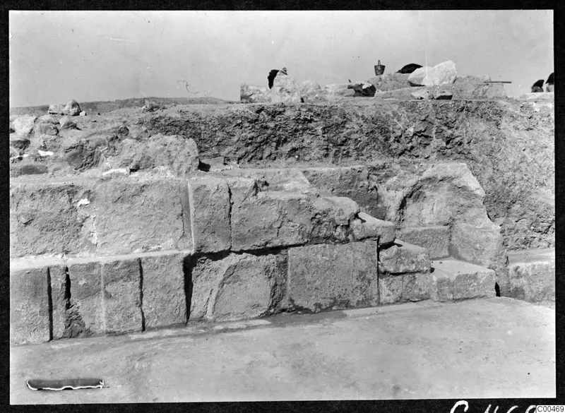 Excavated stone masonry at the theatre at Soli, with a bucket and loose stones on the bank behind.