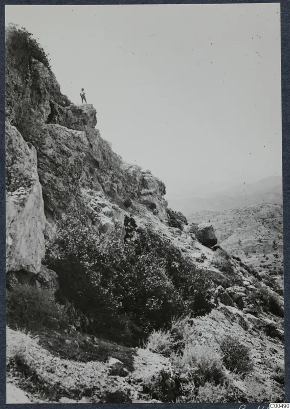 South-west slope at Vouni, a rocky hillside with a single figure standing on a ledge above.
