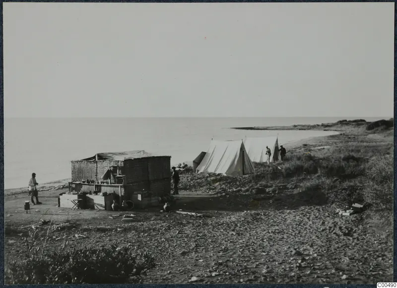 Tents, people and pottery vessels on the shore at Oura