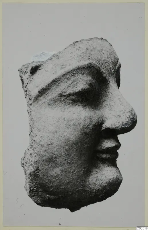 Head fragment of a small statuette in profile facing right, with a broken top and back.