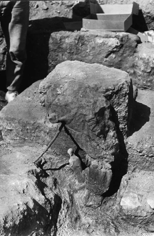 Small terracotta figurine lying in situ among large dressed stone blocks during excavation at Vouni Palace.