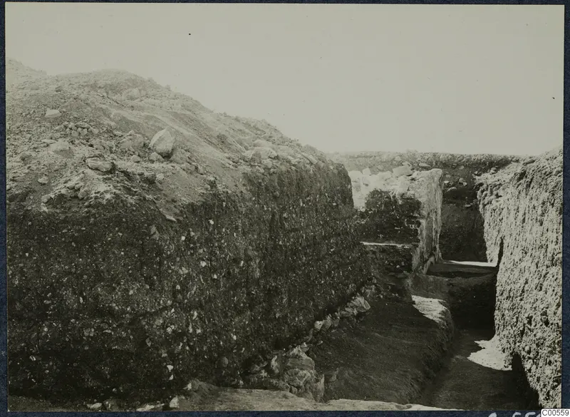 Excavation trench at Vouni with stone walls and a large earth bank on the left.