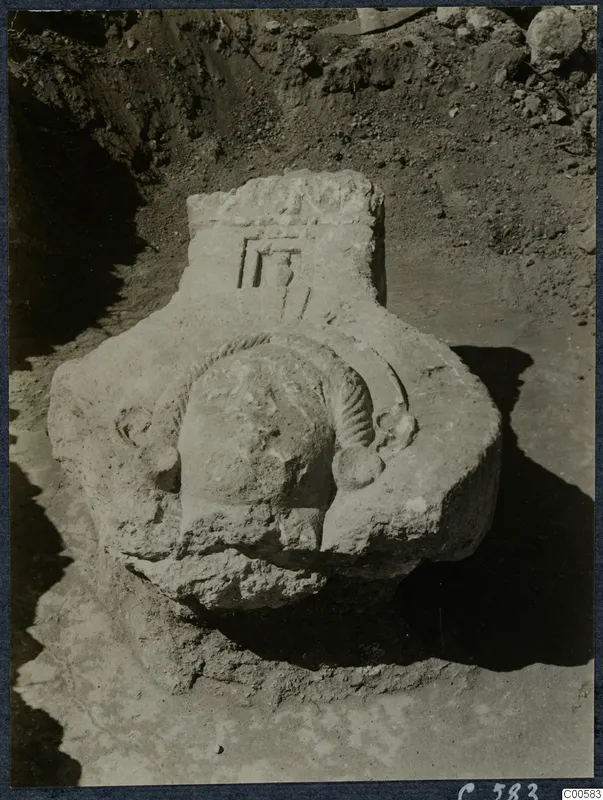 Carved stone block with a relief head-like form, lying in an excavated trench at Vouni Palace