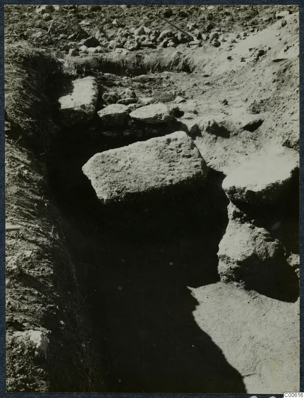 Excavation trench at Vouni with large stone blocks and a peg lying in the soil