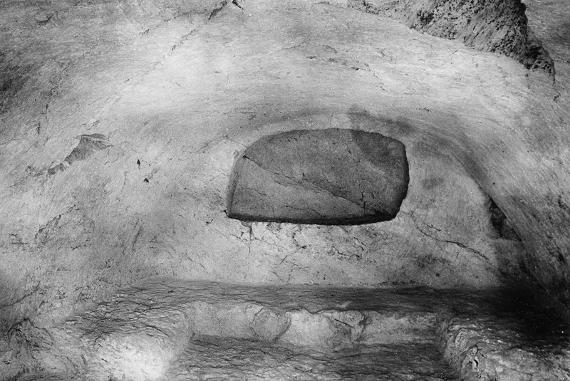Interior of rock-cut Tomb 8 at Vouni, with a rectangular stone slab set into the back wall.