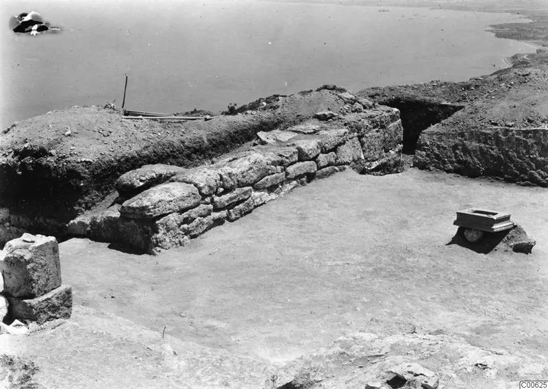 Low stone wall and a small stone block on an excavated area at Vouni palace, with the sea beyond