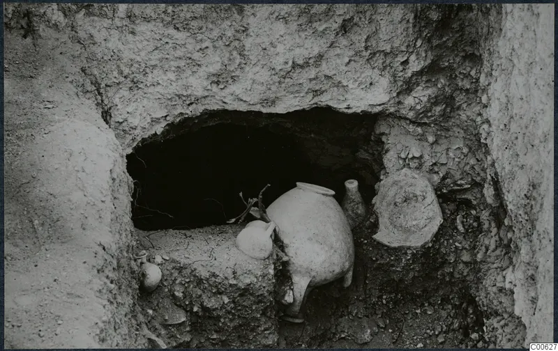 Pottery vessels in front of a rock-cut tomb opening during excavation at Vouni