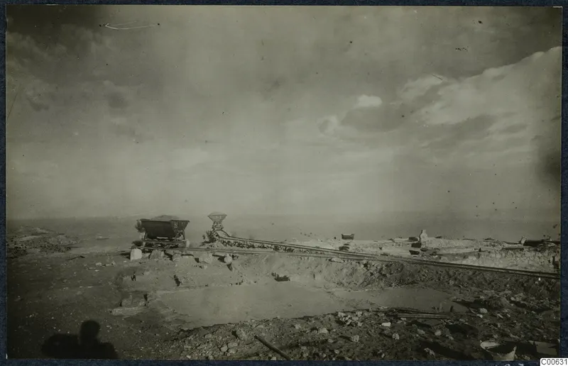 Excavation at the Vouni palace with rails, small wagons and stone walls, with the sea on the horizon