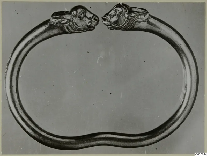 Gold bracelet with two animal heads, facing each other across the open ends of the band.