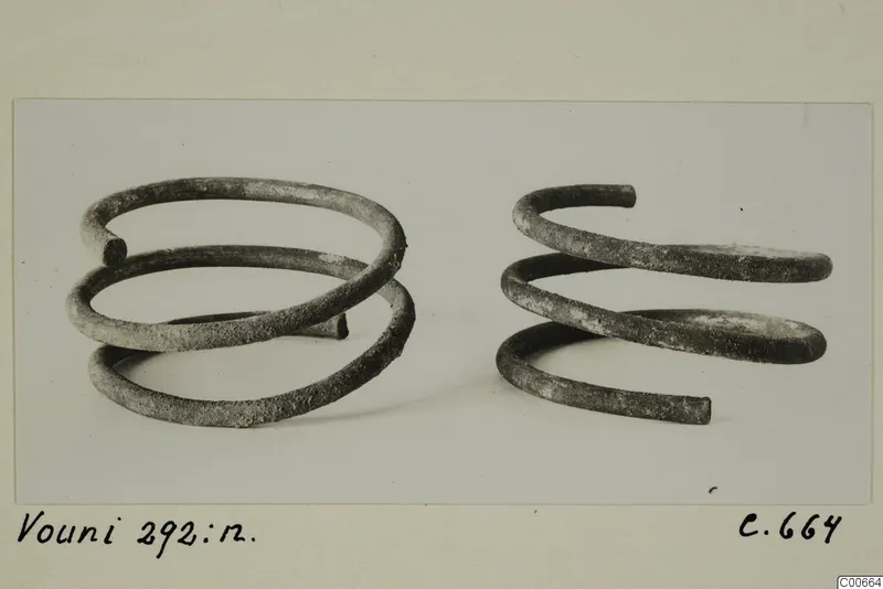 Two spiral metal wire objects, dark and encrusted, from Vouni