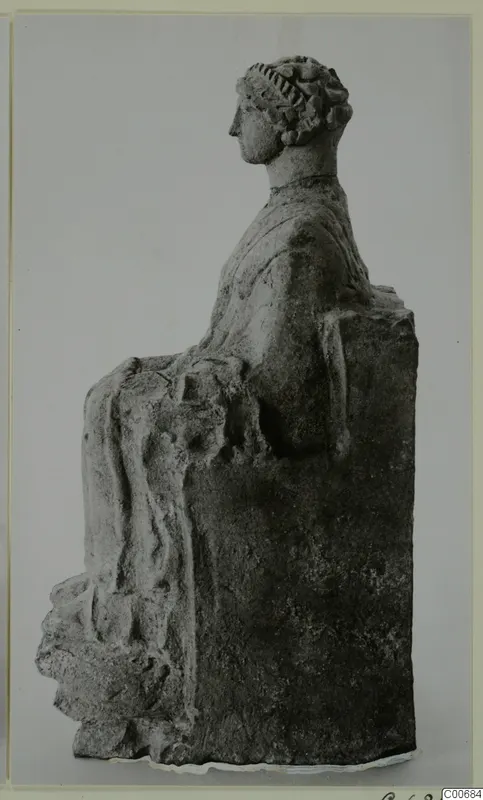 Seated figure in profile, with hair bound up in a band and draped garment over the lap, on a rectangular block seat.