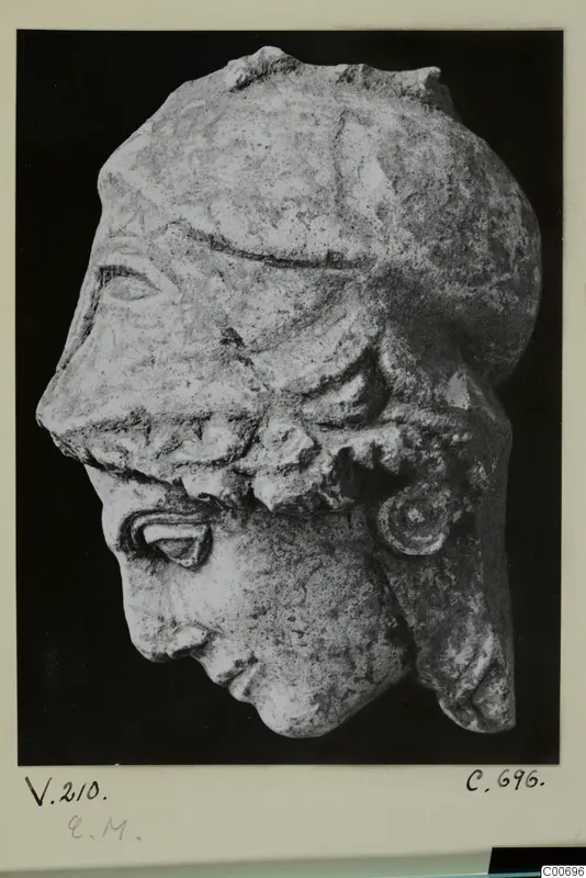 Sculpted limestone head in profile, wearing a helmet, shown against a black background