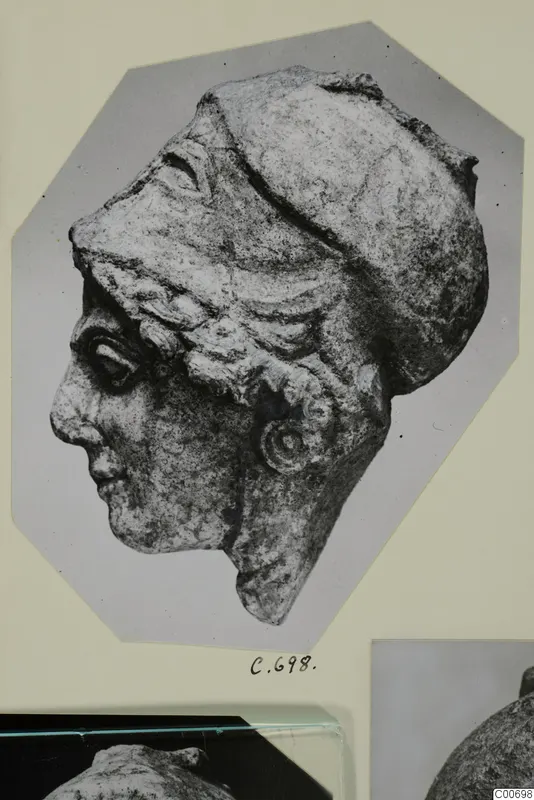 Limestone head in left profile, wearing a close-fitting cap, shown as a photograph on a mounted card