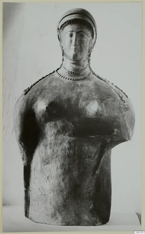 Terracotta bust of a female figure with a close-fitting cap, arms missing, shown against a plain backdrop.