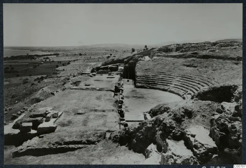 Excavated theatre at Soli with curved stone seating rows, a paved area, and the sea and plain beyond