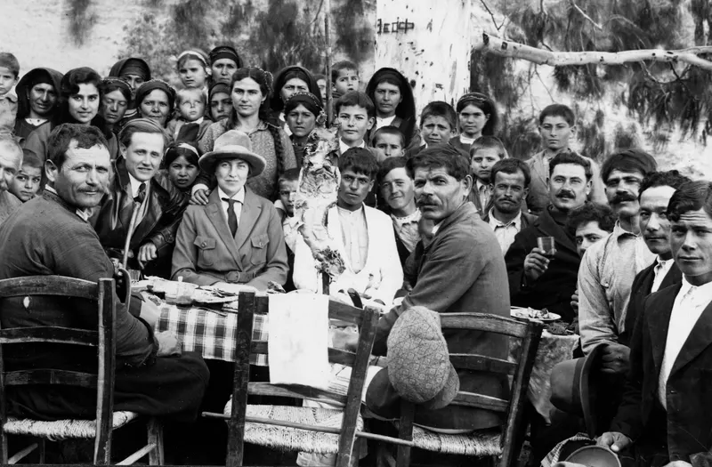 Feast at Galini: a large group gathered around a table set outdoors under trees.