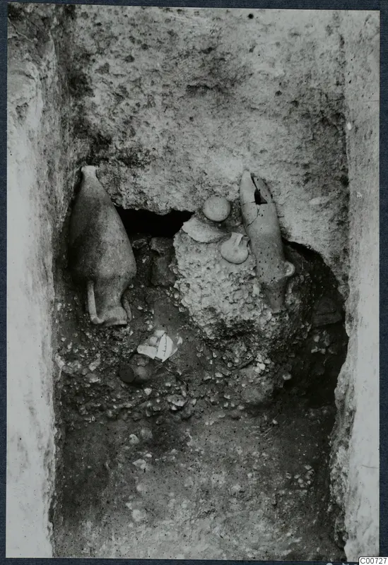 Pottery vessels lying in a narrow rock-cut excavation cutting at Vouni