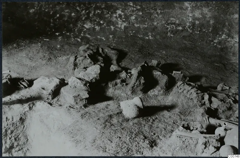 Tomb 11 at Milia: excavated tomb chamber floor with skeletal bones and small vessels in place