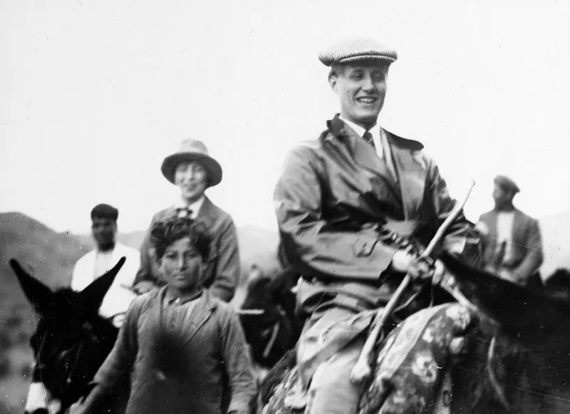Riders on horses and mules on the way to Galini, one man in a flat cap smiling and holding a long stick