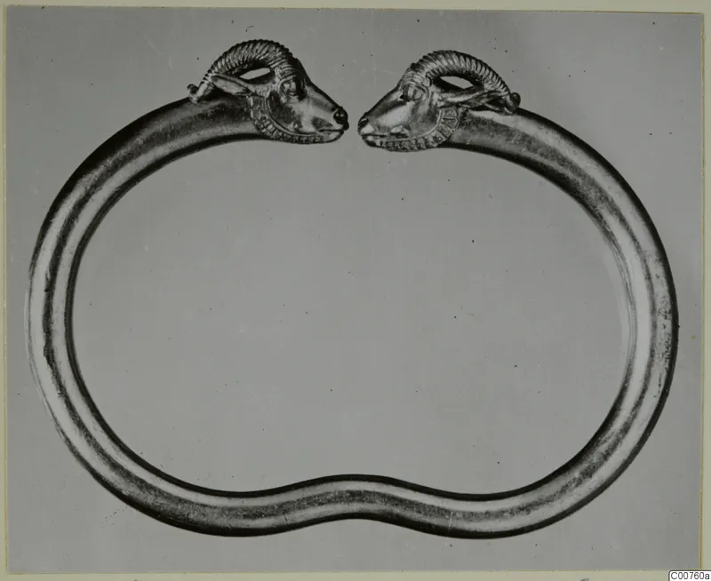 Gold bracelet with two animal heads with curled horns, facing each other across a gap