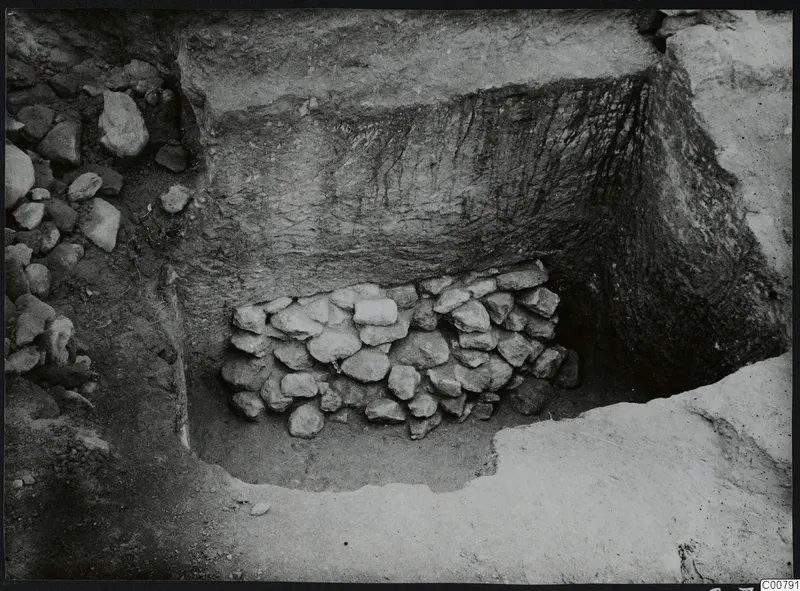 Excavation trench at Plakes, Lapithos, with a heap of stones set against the back face of the cut.