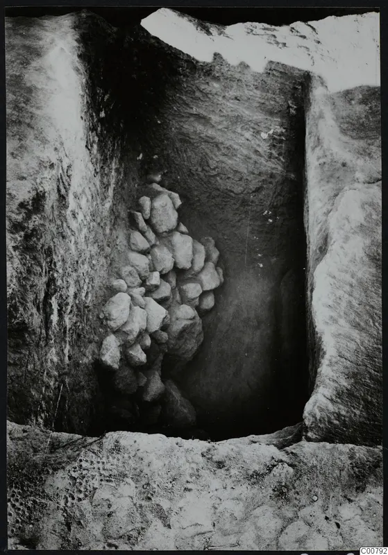 Excavation trench at Plakes, Lapithos, with a heap of stones set against one wall.