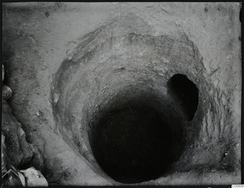 Excavation shaft at Plakes, Lapithos, seen from above, with stones at its edge.