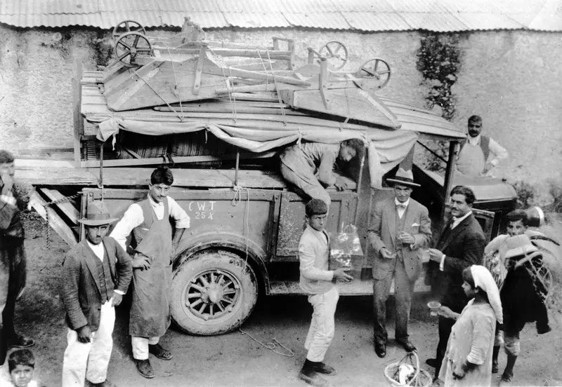 Men and children beside a lorry at Lapithos, loaded with wheelbarrows and wooden frames under a tarpaulin