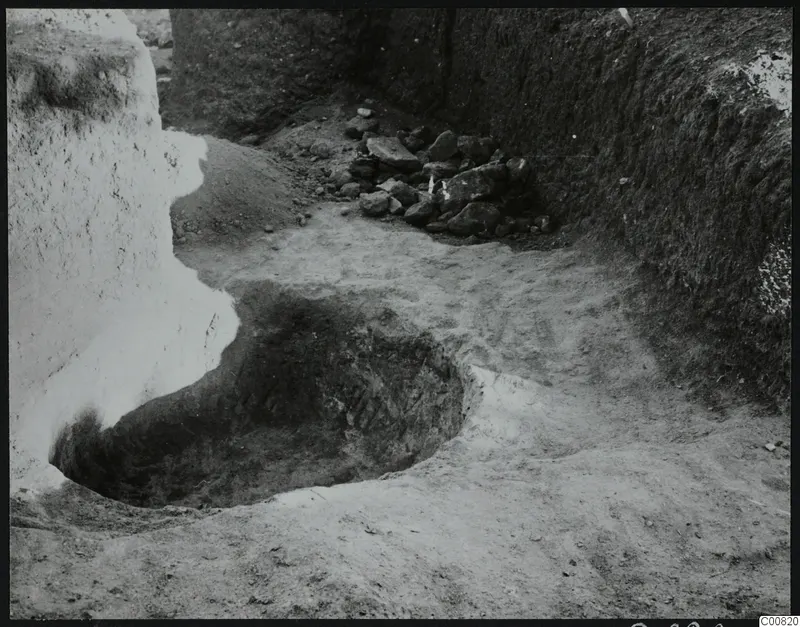 Excavation at Plakes, Lapithos, with a pit and a heap of stones against an earth section