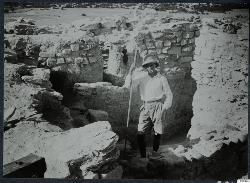 Erik Sjöqvist standing by the west wall at Idalion, holding a long pole among excavated stone walls.