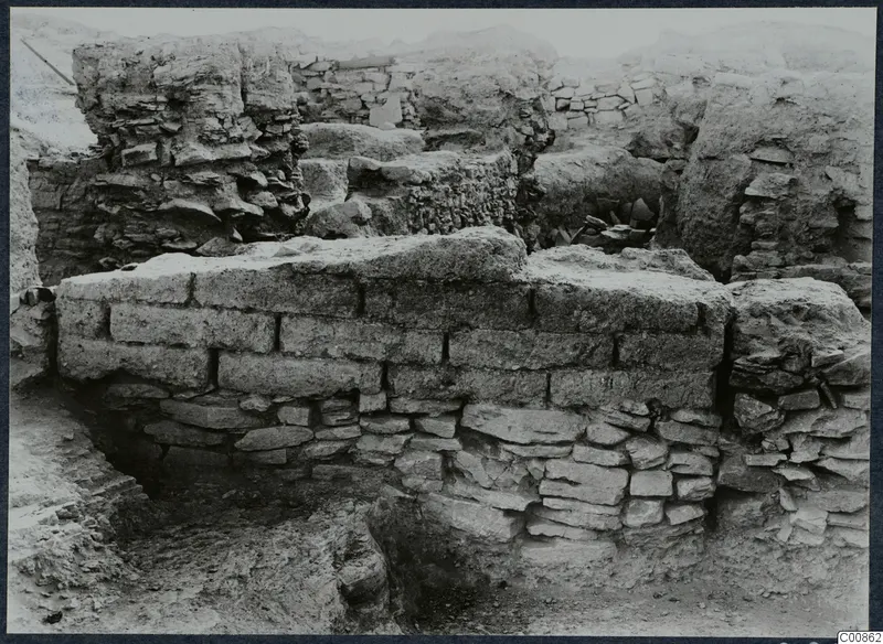 Excavated wall of stone and mud brick at the Idalion acropolis, with rubble and ruined walls behind it.