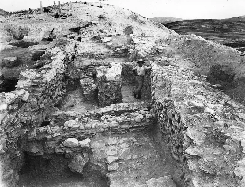 Excavated stone walls in L 8 at Idalion, with a man in a hat standing between them
