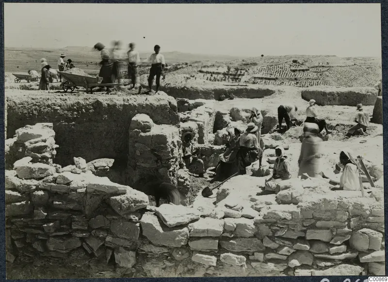 Workers excavating stone and mud-brick walls at F7, Idalion, with a wheelbarrow and spades